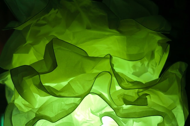 Frosted glass card glowing softly in emerald green, showcasing Semiscape Textiles' sleek fabric rolls under bioluminescent lighting.