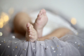 Close-up of a baby’s tiny feet resting on a sea green blanket, symbolizing comfort.