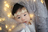 A delicate newborn canopy softly illuminated by a warm pendant light casting gentle shadows.