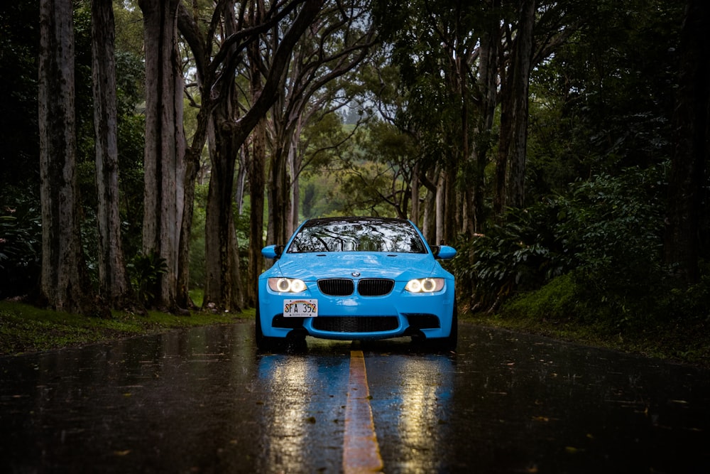 blue BMW car passing through forest