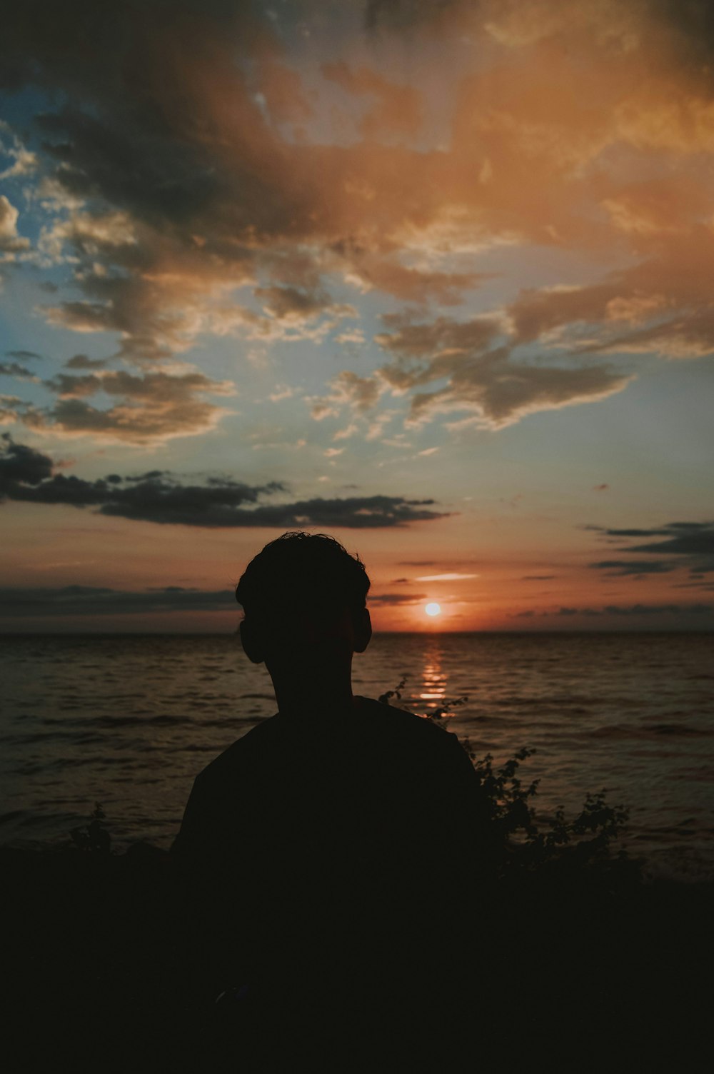 silhouette photography of person standing beside body of water