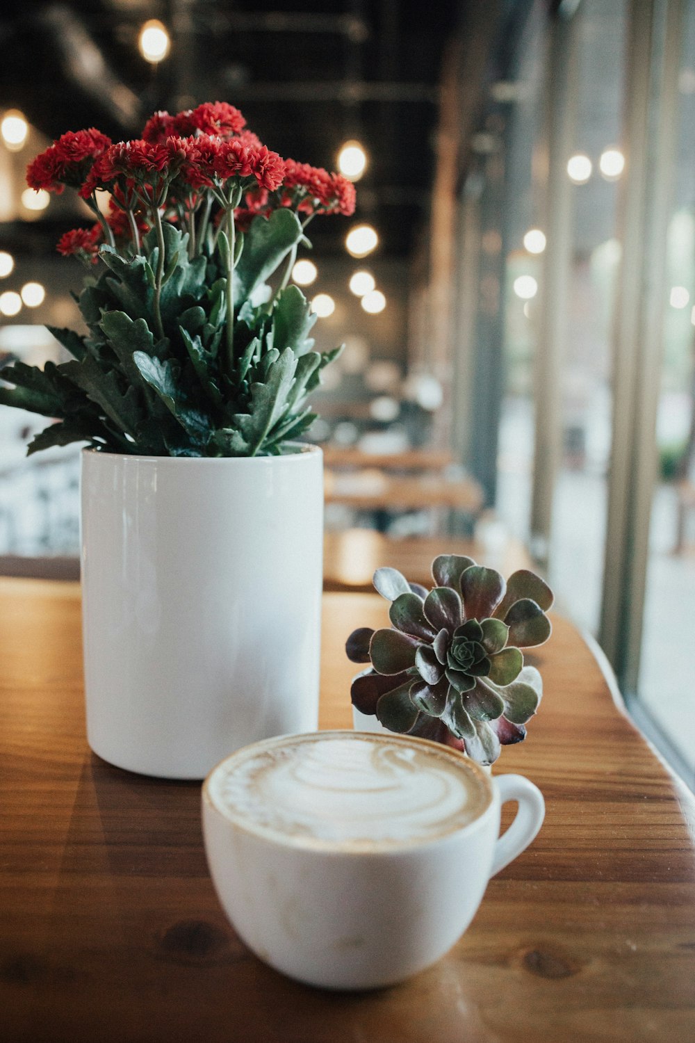 white ceramic mug beside white ceramic flower vase with green plant