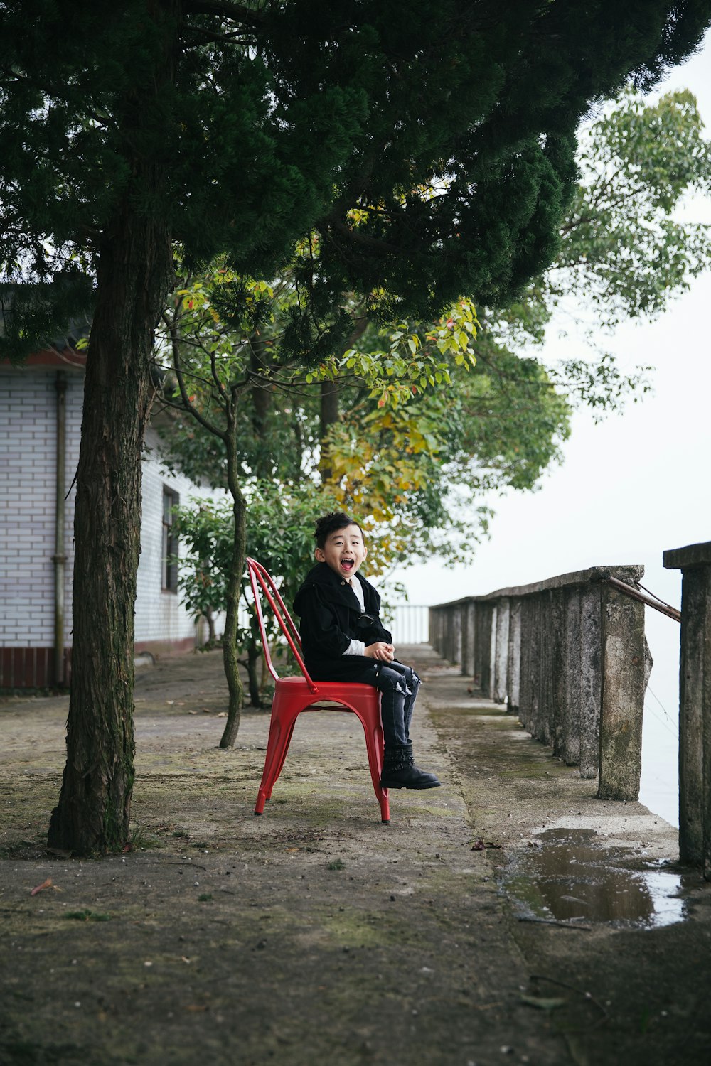 boy sitting on red monobloc chair