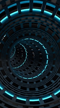 A futuristic spiral tunnel with glowing blue lights lining the circular edges, creating a visually striking pattern of concentric circles. The structure appears metallic, with a dark, sleek design that suggests depth and infinity.