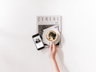 Close-up of hands reviewing music publishing documents beside a cup of coffee.