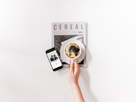 Close-up of hands reviewing music publishing documents beside a cup of coffee.