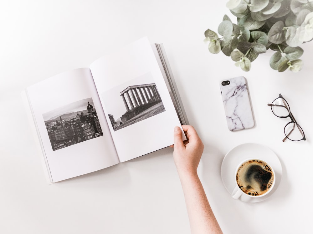 person holding opened book beside iPhone