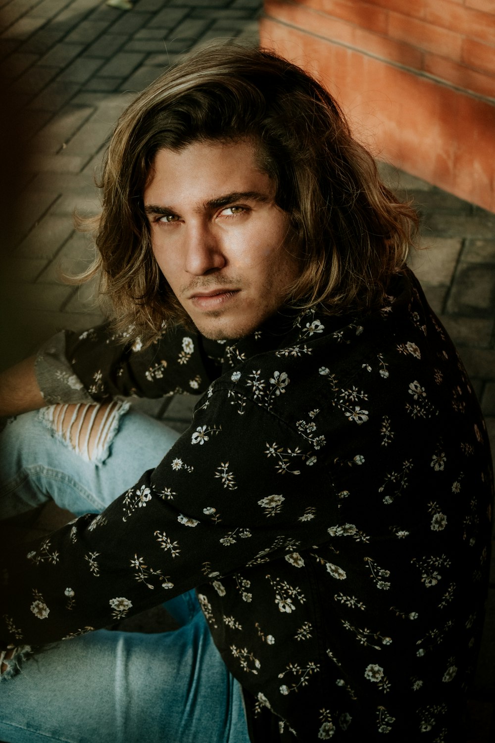 man sitting on gray brick pavement