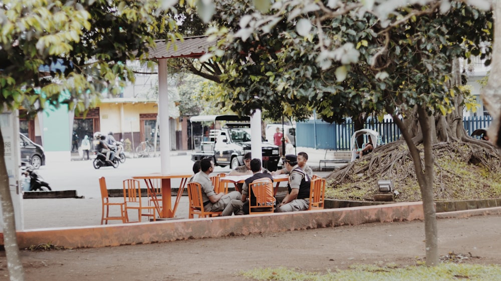 men talking to each other while sitting on chairs near trees