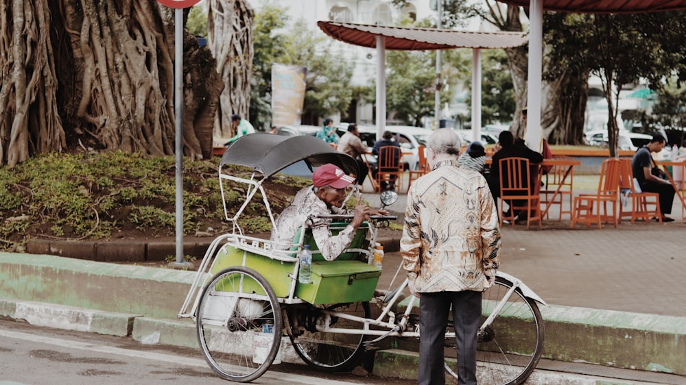 man sitting in trike talking to another person standing in front of him