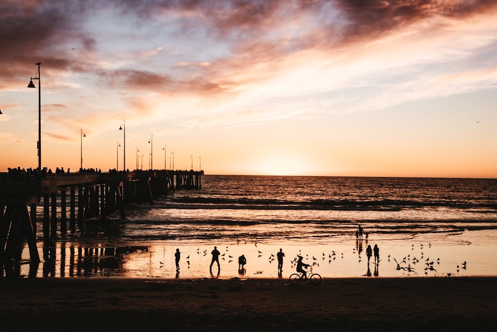Silhouette von Menschen auf Meerwasser während der goldenen Stunde