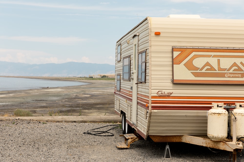 an rv parked on a gravel road next to a body of water