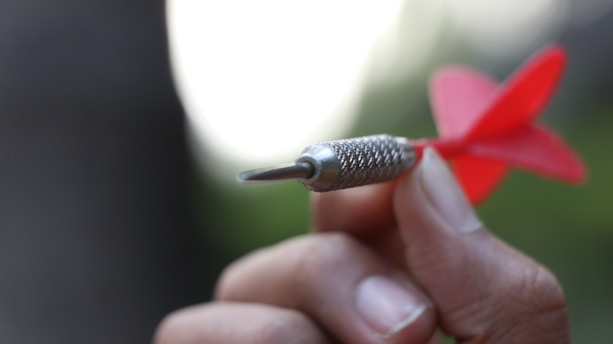 A para darts athlete aiming carefully during a competition, with a focused expression and adaptive equipment visible.