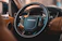 Close-up of a sleek car dashboard with an elegant perfume bottle resting on it.