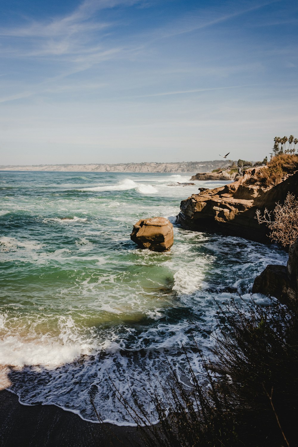 Fotografia naturalistica delle onde che si infrangono sulla costa rocciosa durante il giorno