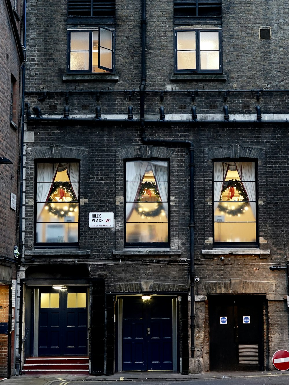 three green Christmas wreaths behind glass windows