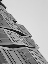 Wide-angle shot of a modern building facade with sharp geometric shapes against a clear sky.