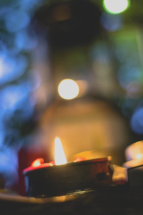 A softly lit candle with a bluegrass field backdrop at sunset.