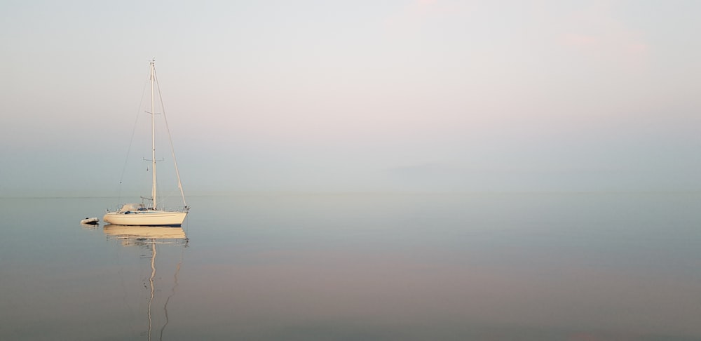 white sailboat at middle of sea