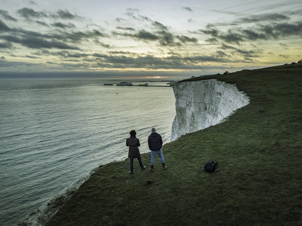 two people standing near body of water