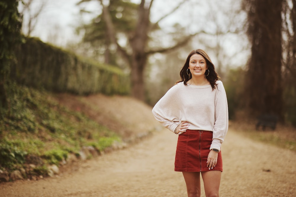 woman in white sweater and red mini skirt standing in the middle of road