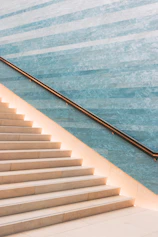 A sleek matte black metal staircase railing contrasting with warm beige stone steps.