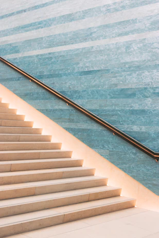 A sleek matte black metal staircase railing contrasting with warm beige stone steps.
