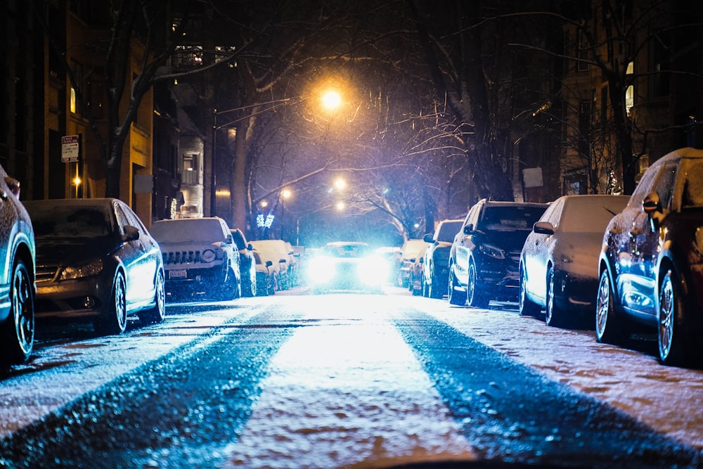 Coches aparcados a ambos lados de la calle durante la noche nevada