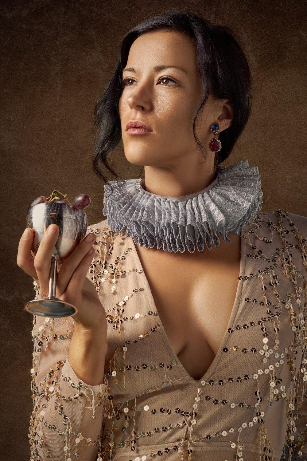 woman holding silver wine glass with purple grapes