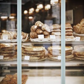 A bakery display with various pastries and breads, including croissants, chausson pommes, and pain choco. The items are neatly arranged in baskets with price tags, creating a warm and inviting atmosphere.