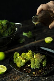 person pouring cola on broccoli