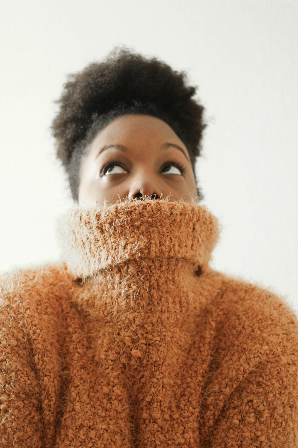 woman wearing orange turtle neck sweat shirt looking upward