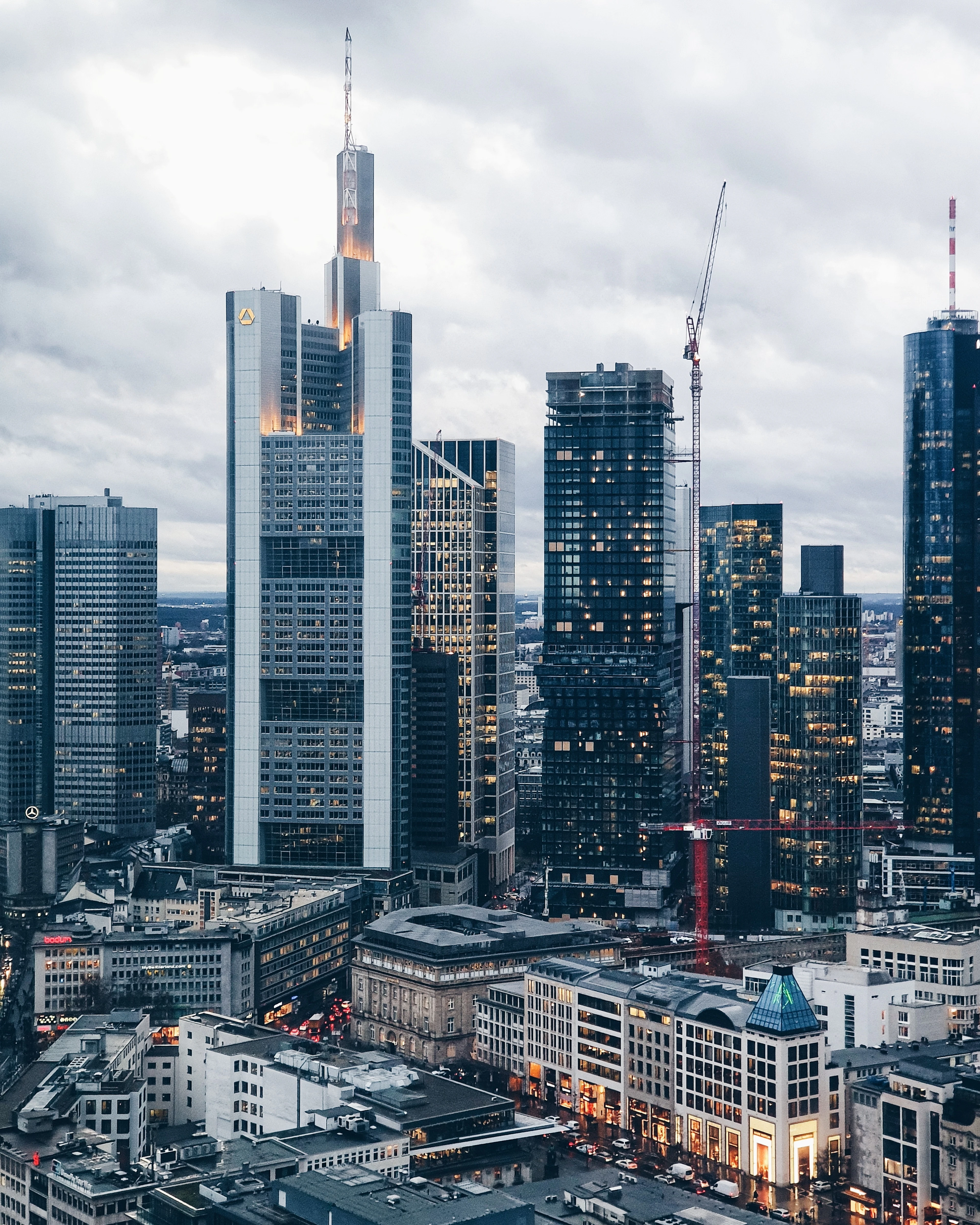 The Frankfurt skyline from above at dusk, glass towers lit against a dark sky