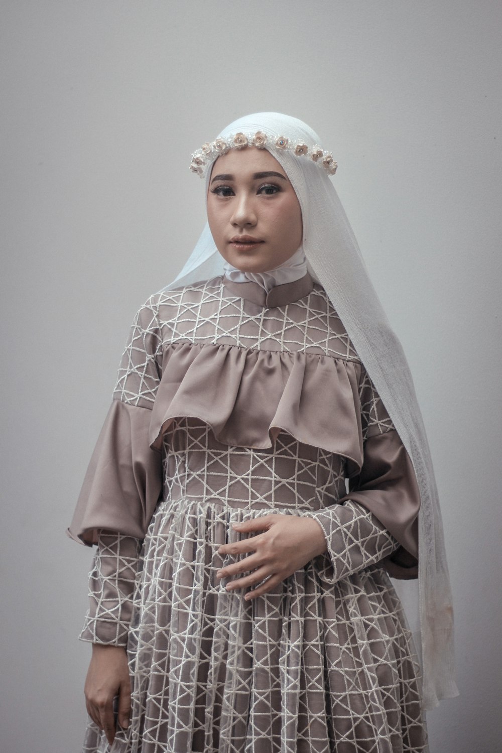 woman in gray abaya standing beside wall