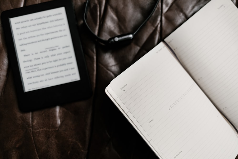 black e-book reader beside open book