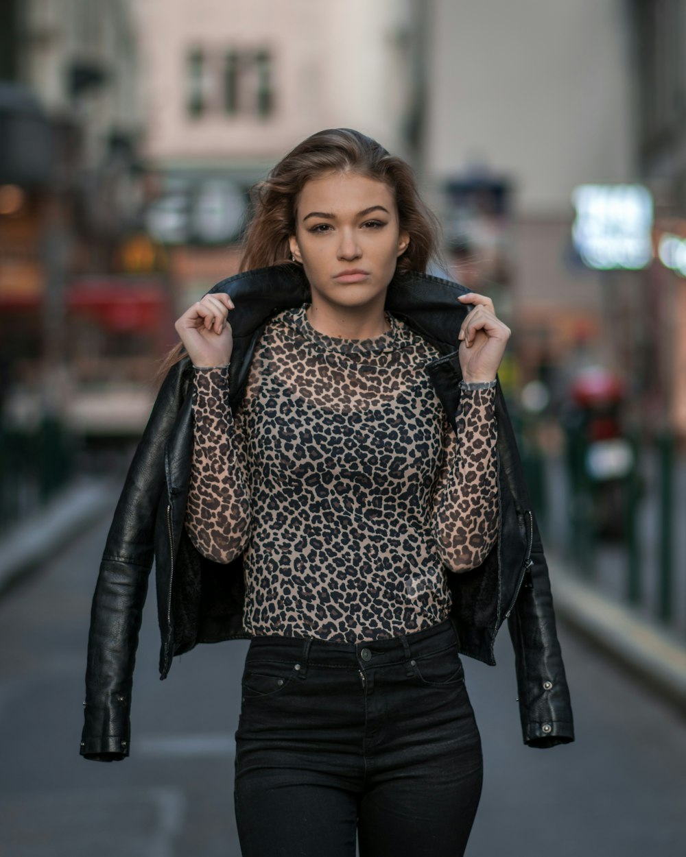 woman holding black jacket while standing on road