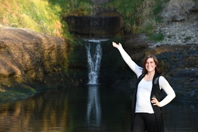 A happy woman aged 50, enjoying a serene moment by a waterfall.