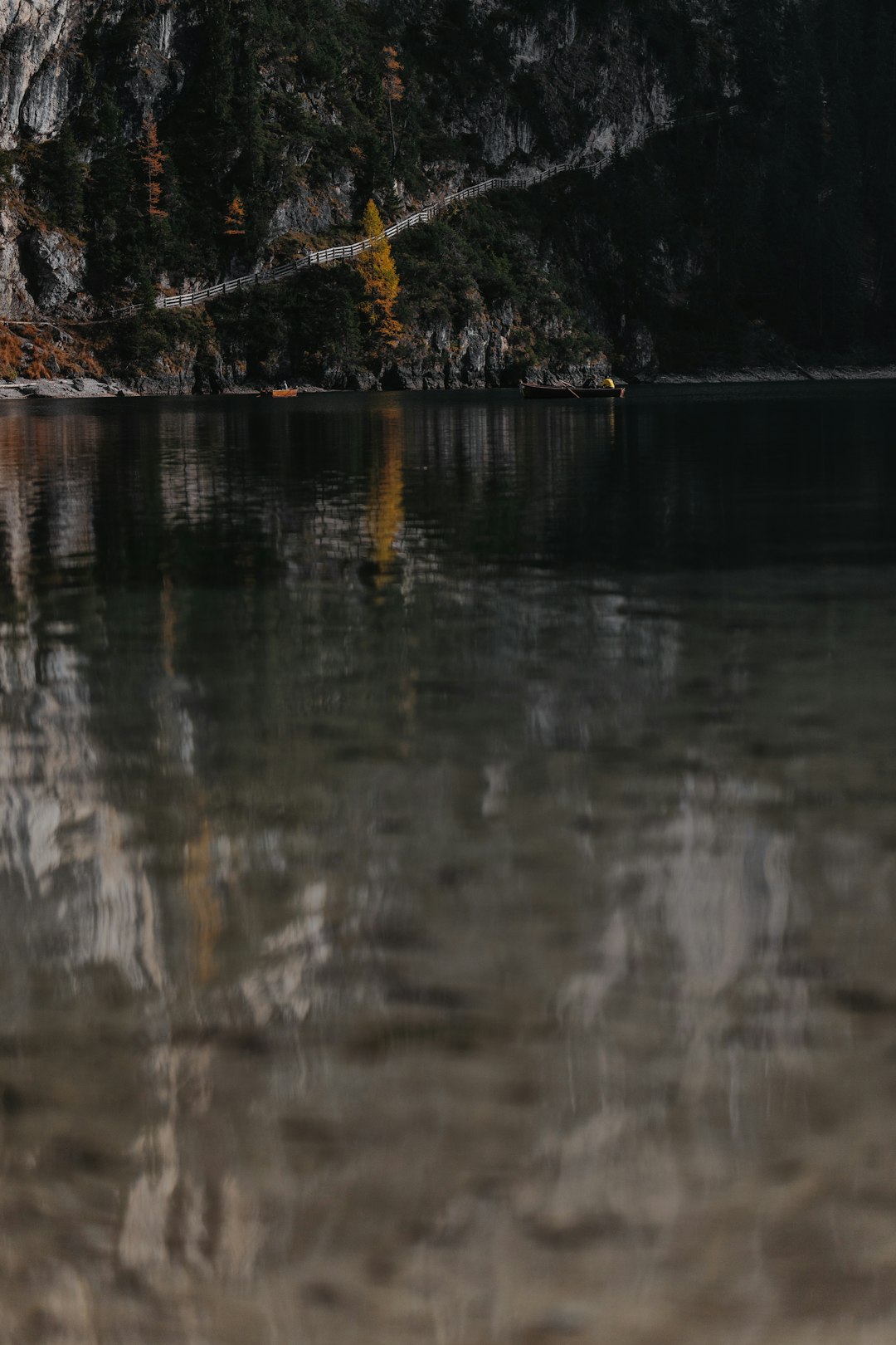 calm body of water near rock mountain during daytime