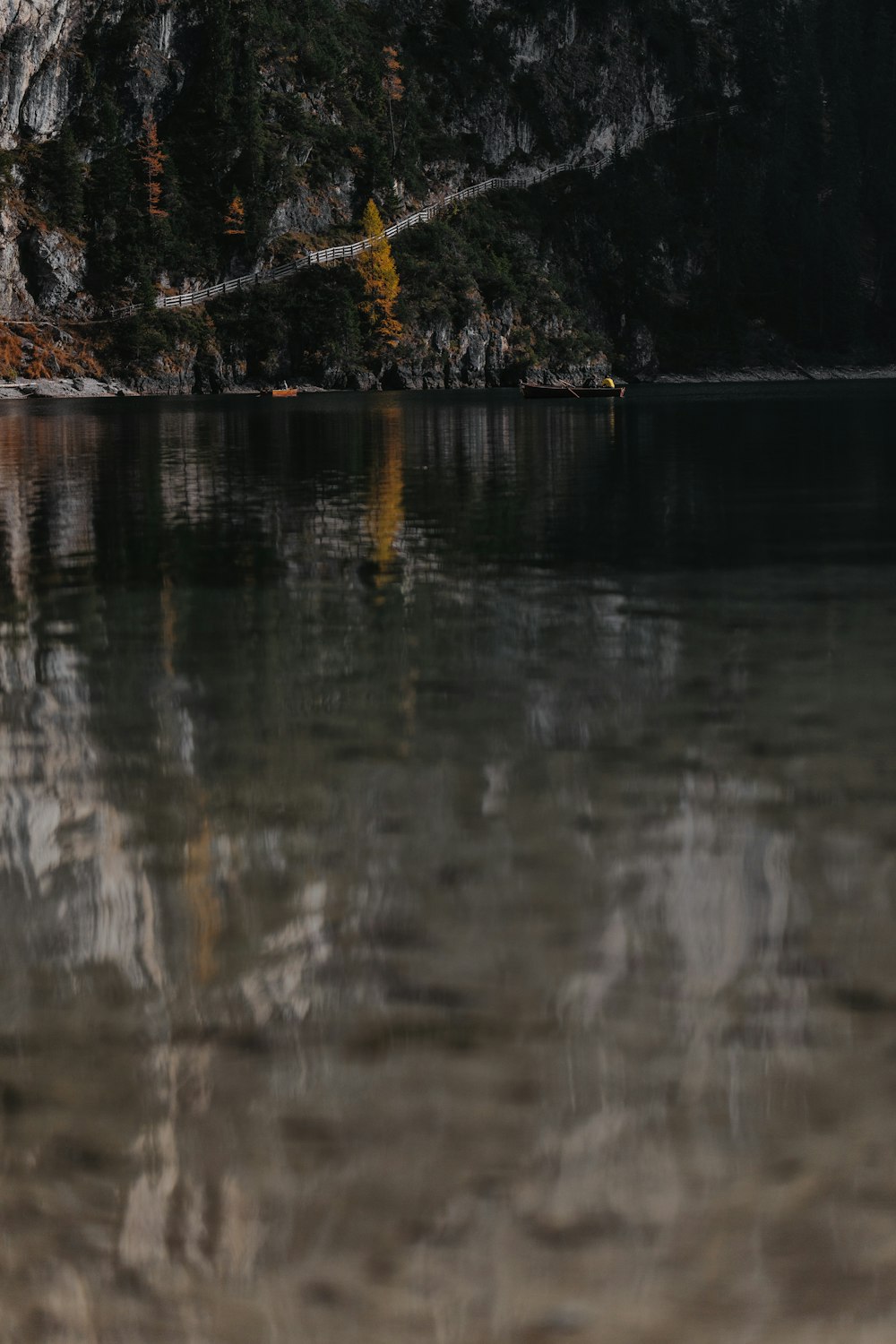 calm body of water near rock mountain during daytime