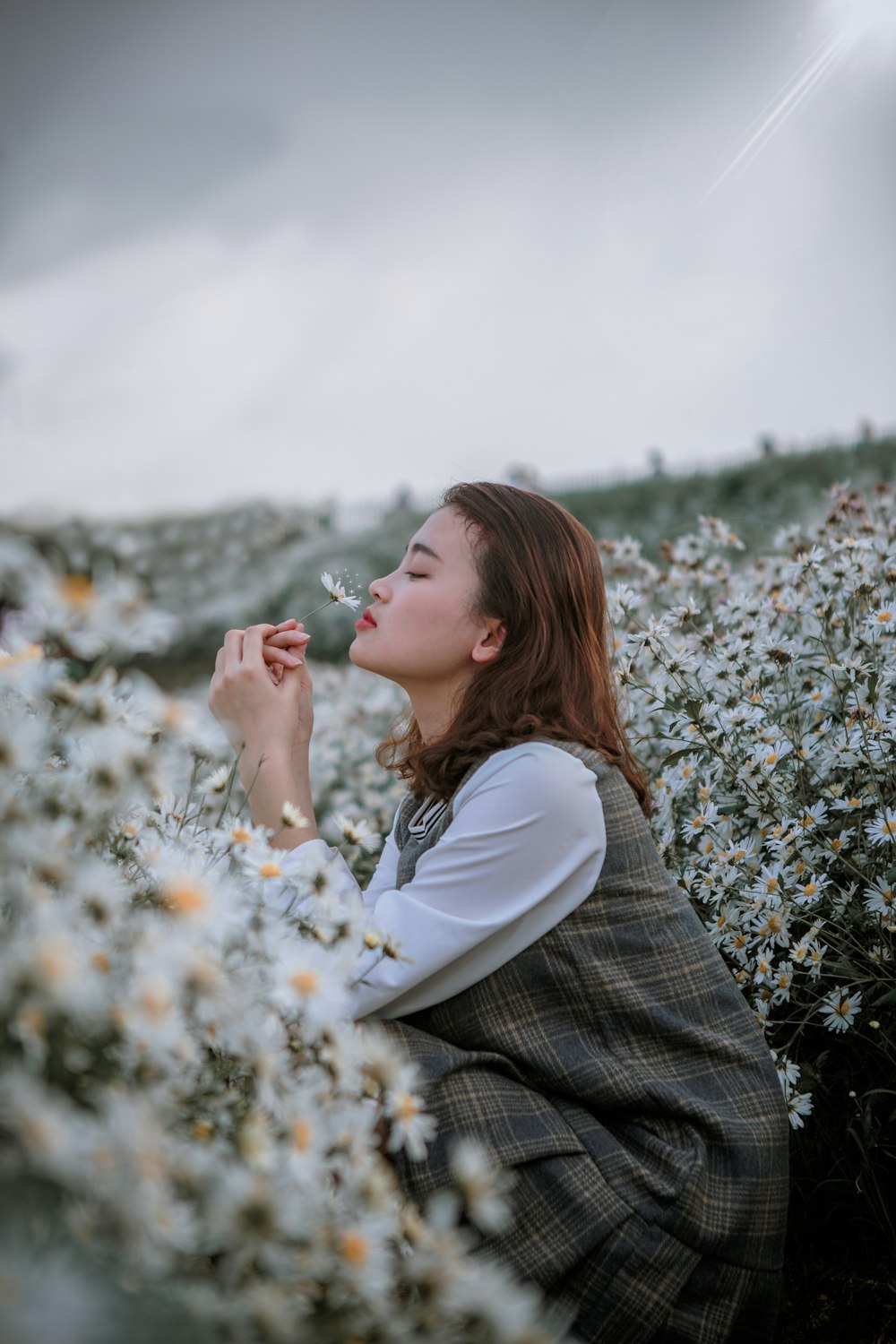 Fotografia selettiva di messa a fuoco della donna che sente l'odore del fiore