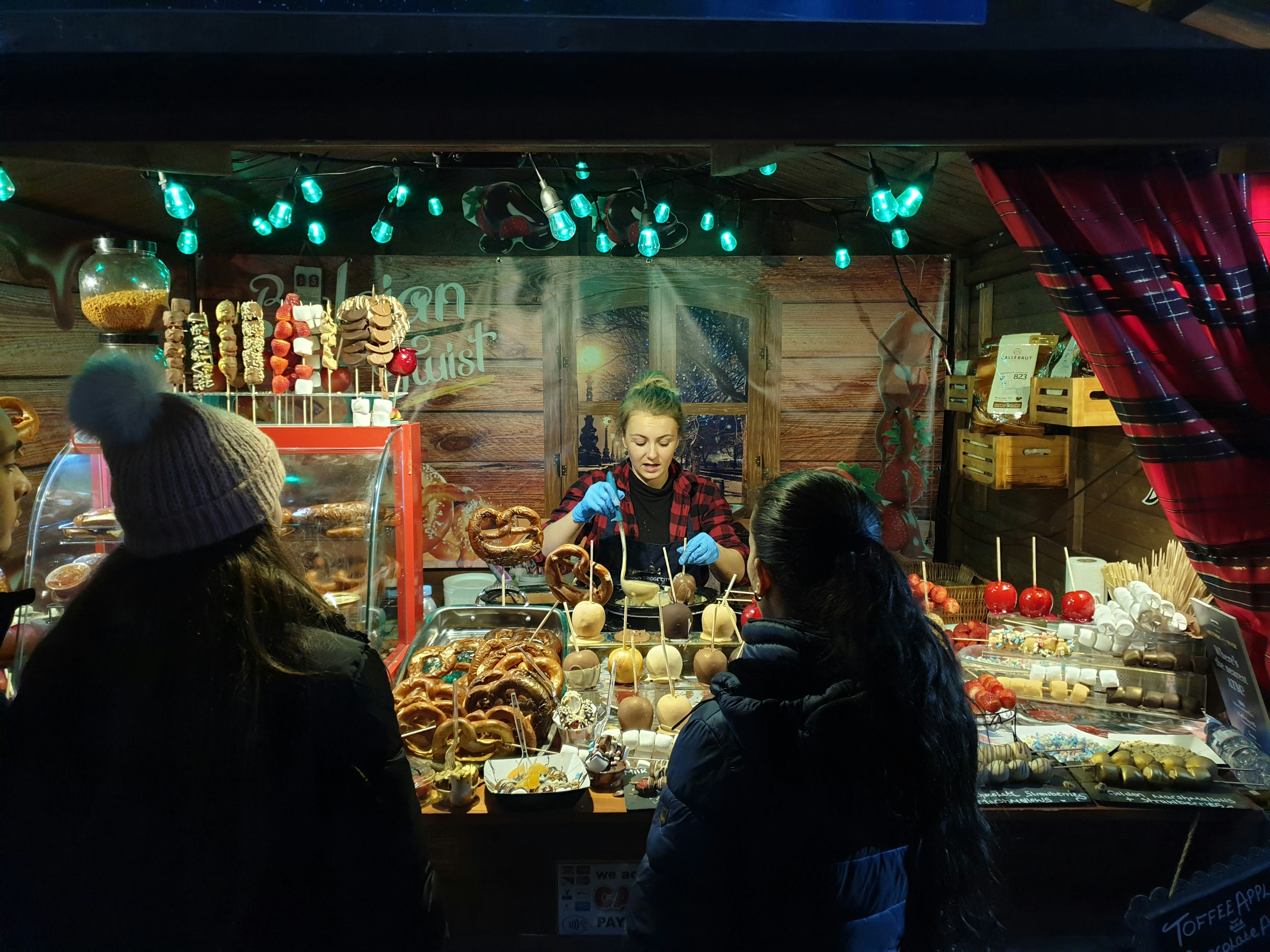 Ice cream catering setup at a festive outdoor event, warm fairy lights, dark atmospheric background, rich shadows