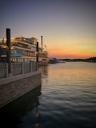 The Libertas docked alongside a lush green riverbank at sunset.