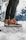 A customer showcasing durable winter boots from embernest ventures in a snowy landscape.