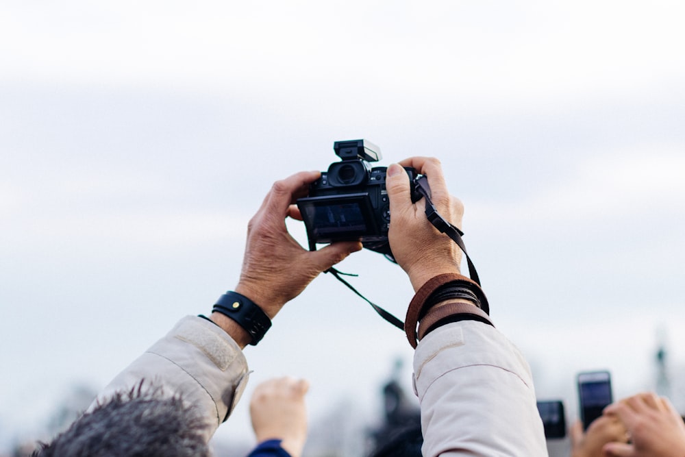 person holding black DSLR camera taking picture during daytime