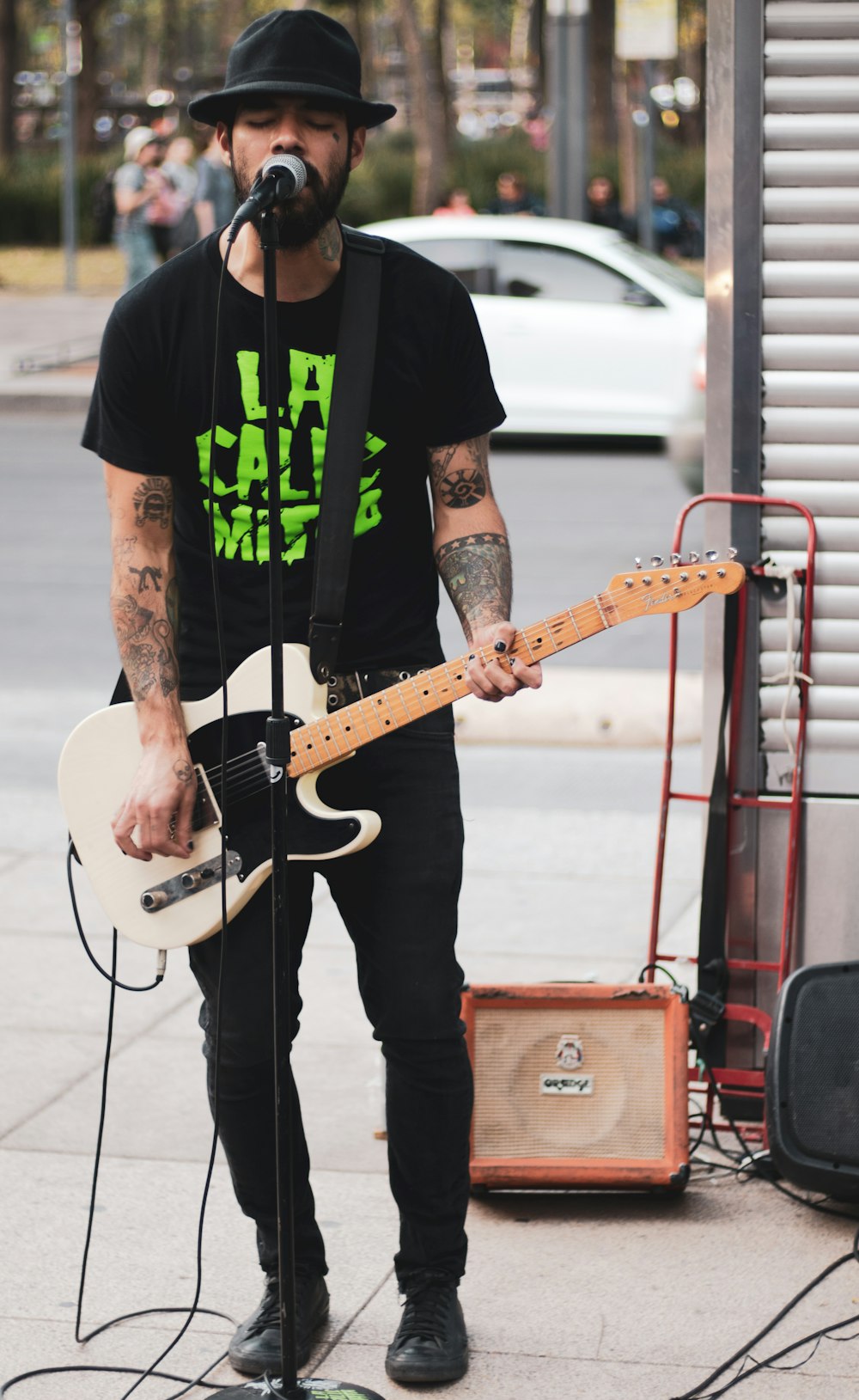 man playing telecaster guitar while singing on street