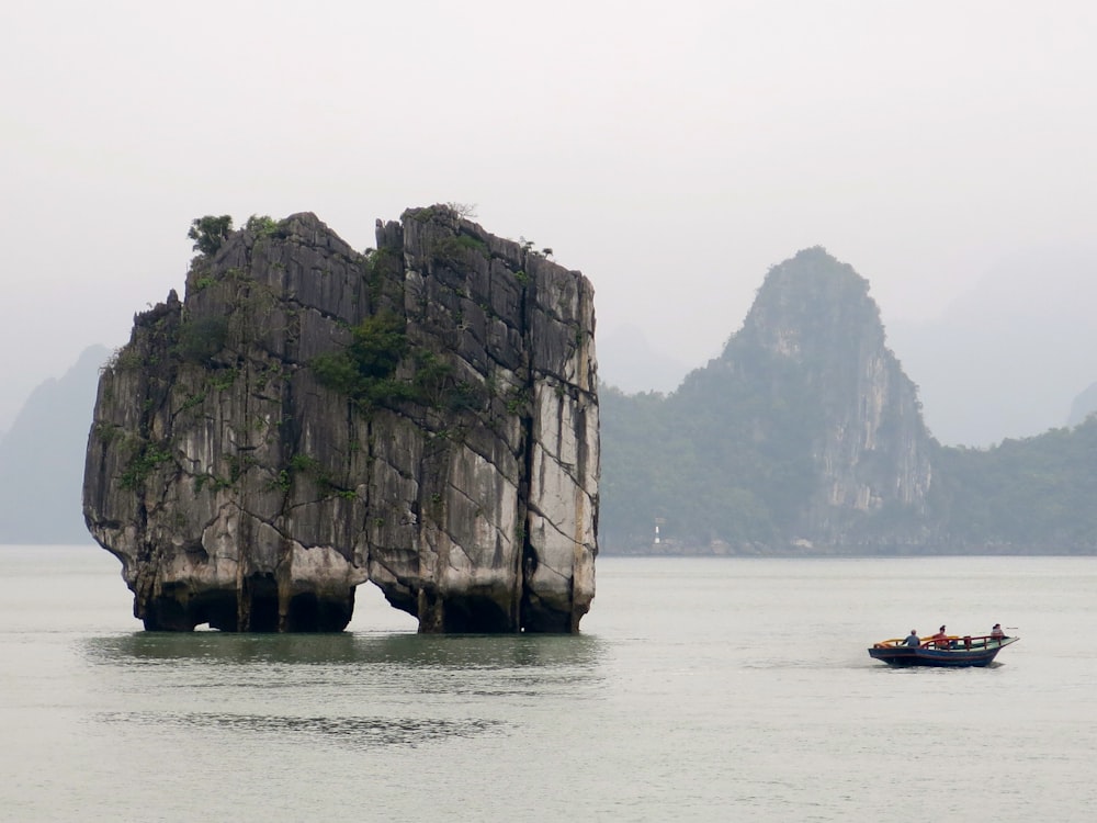 sailing boat near rock mountain at daytime