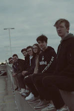 Group of diverse friends rocking navycrew streetwear, laughing and hanging out on a city rooftop at sunset.