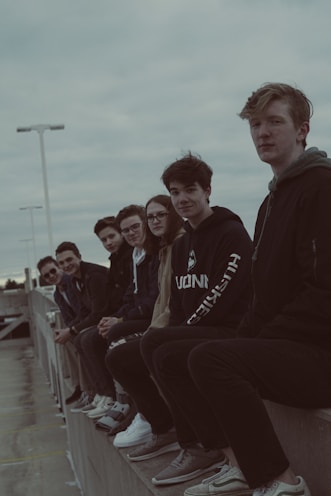 A group of friends wearing nameless faceless jackets, laughing together on a city rooftop.