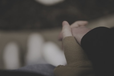 A close-up of intertwined fingers with a blurred romantic background.