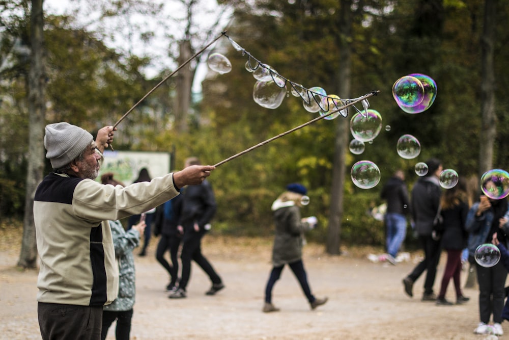 man holding stick while making bubbles